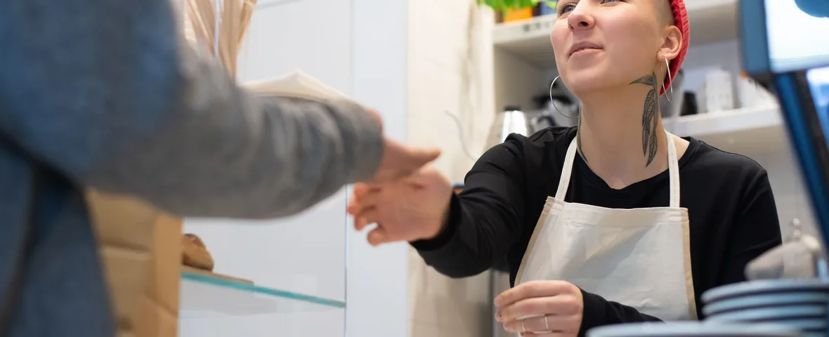 Australian retail worker serving a customer at a shop counter, one of millions covered by the July 2026 award rate increase