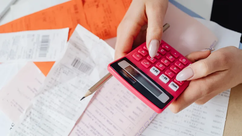 Worker checking pay documents and receipts with a calculator to verify the July 2026 award pay increase