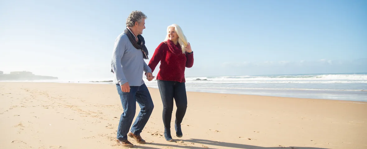 Retired Australian couple walking along the coast, representing the retirement lifestyle super benchmarks are designed to fund