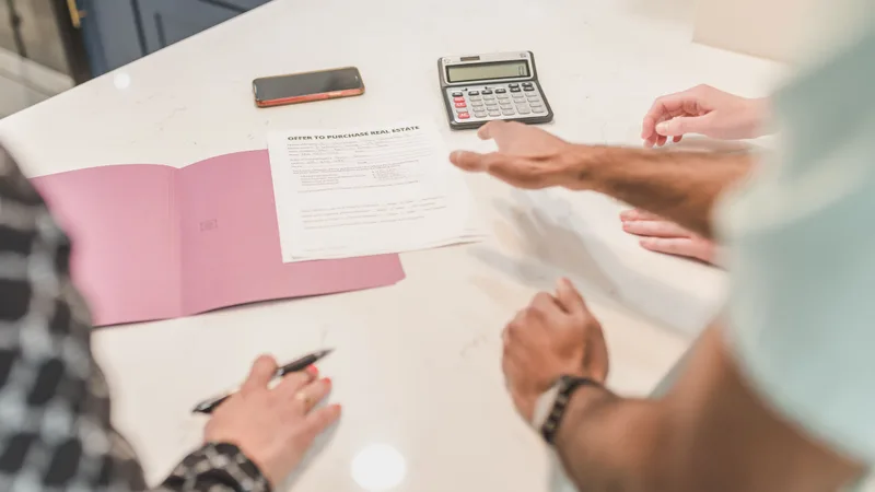 Investor working through sale timing figures at a desk with a calculator and property documents